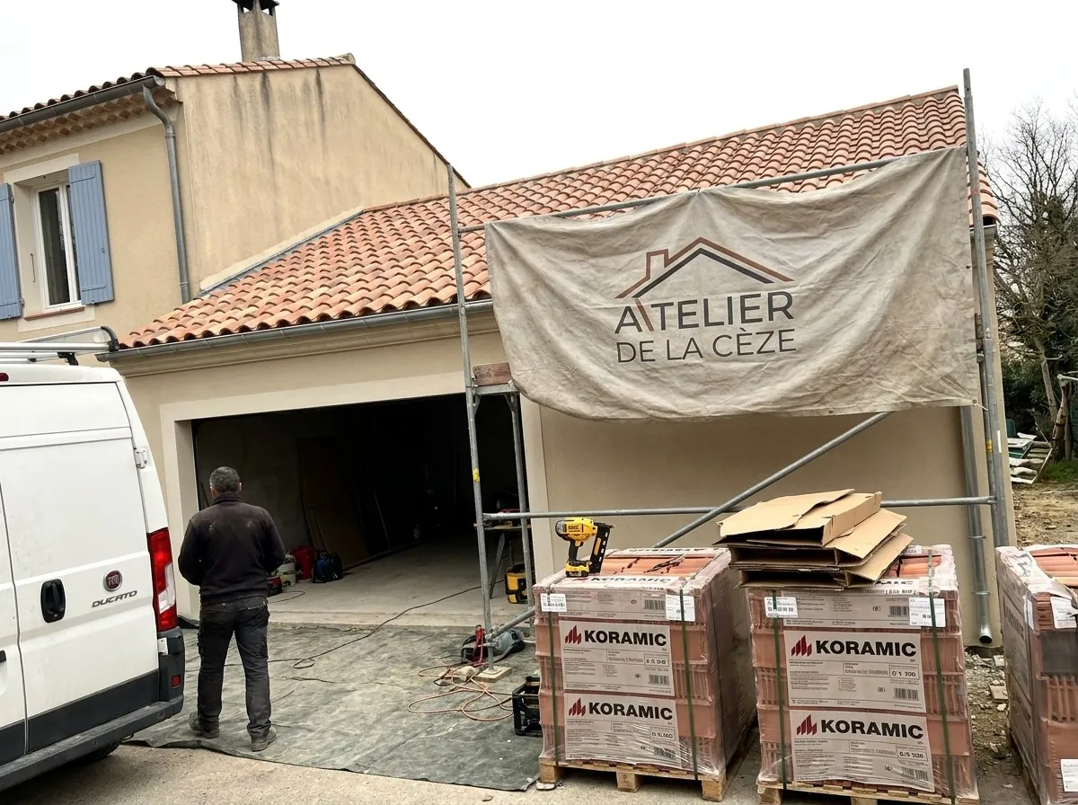 Chantier de couverture de l'Atelier de la Cèze à Bagnols-sur-Cèze : échafaudage, bâche au nom de l'atelier et palettes de tuiles neuves